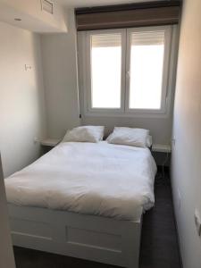 1 dormitorio con 1 cama blanca y ventana en Avenida de las Piletas, en Sanlúcar de Barrameda