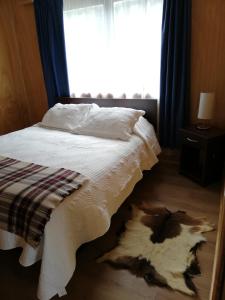 1 dormitorio con 1 cama con manta blanca y ventana en Puesto Cánogas Hostal, en Villa O'Higgins