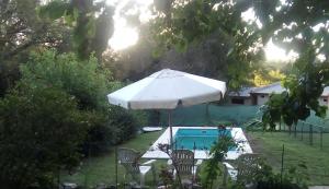 a white umbrella and chairs next to a swimming pool at Evergreen in La Cumbre