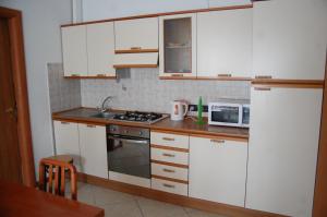 La cuisine est équipée de placards blancs, d'une cuisinière et d'un four micro-ondes. dans l'établissement La finestra sul parco, à Vérone