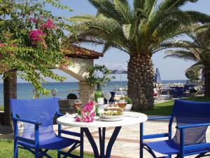 uma mesa e cadeiras com uma mesa e uma palmeira em Zakantha Beach em Argasi