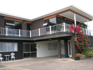 a building with a balcony with flowers on it at Harbour Inn in Whangamata