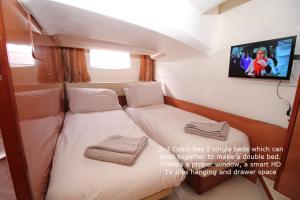 um pequeno quarto com duas camas e uma televisão em Zen Dog Luxury Motor Yacht em Lymington