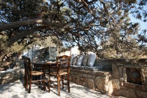 une table et des chaises assises sous un arbre dans l'établissement The Old ''Stony'' Mitatos, à Plage d'Aliko