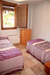 een slaapkamer met 2 bedden, een dressoir en een raam bij Apartamento Angel e Isabel in Alquézar
