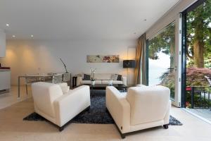 a living room with two white chairs and a table at Giardino Violetta in Lugano