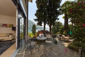 eine Terrasse mit einem Tisch, Stühlen und einem Sofa in der Unterkunft Giardino Violetta in Lugano
