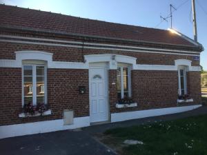 a brick building with a white door and windows at Le Cottage in Harbonnières