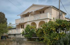 a house with an orange tree in front of it at Apartments Slavica in Luka