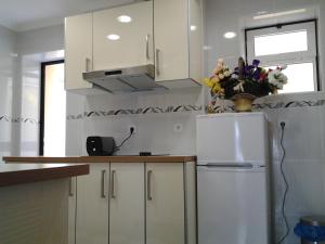 a kitchen with white cabinets and a refrigerator with a vase of flowers at Baixa GuestHouse in Lisbon