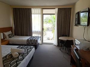 um quarto de hotel com duas camas e uma porta de vidro deslizante em Molly Morgan Motor Inn em Maitland