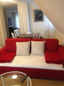 ein rotes Sofa im Wohnzimmer mit einem Tisch in der Unterkunft Düsseldorf Messe -Apartment Milan in Düsseldorf