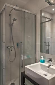 a bathroom with a sink and a shower with a glass door at Hotel Les Terres Blanches in Chatou
