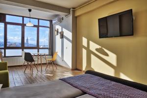 a bedroom with a tv and a table with chairs at Panorama studio in Sibiu