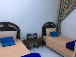 two beds in a room with blue pillows at Dar El Karam in Rabat