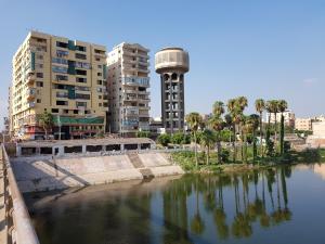 ein Wasserkörper mit Gebäuden und einem Uhrturm in der Unterkunft Al Mansoura Apartment in Mansoura