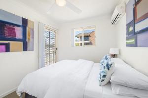a white bedroom with a bed and a window at Seabreeze 4 on Lawson Street in Byron Bay