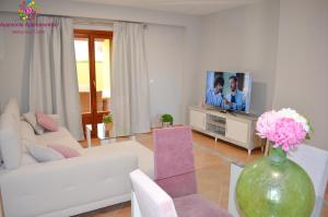 uma sala de estar com um sofá branco e uma televisão em MARINA AZUL GOLF em Ayamonte