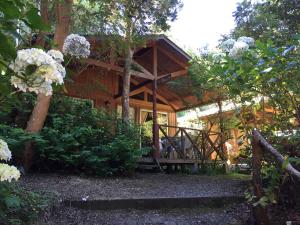 a cabin with a wooden porch in the woods at Cabañas el Bosque Patagónico in Frutillar