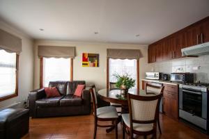 a kitchen and living room with a table and a couch at Departamentos Costanera in Punta Arenas