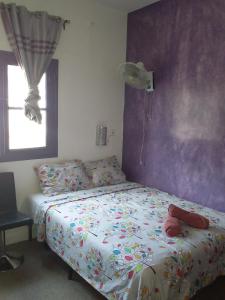 a bedroom with a bed and a purple wall at LOGEMENT DE 2 SYMPATIQUES PIECES in Ouakam