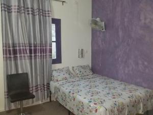 a small bedroom with a bed and a chair at LOGEMENT DE 2 SYMPATIQUES PIECES in Ouakam