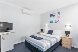 1 dormitorio con 1 cama y TV de pantalla plana en Wattle Grove Motel Maryborough en Maryborough