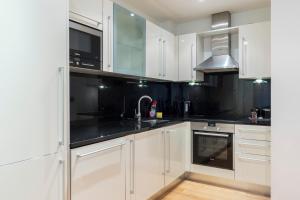 una cucina con armadietti bianchi e ripiani neri di East Croydon Apartments - Just 3 mins walk to East Croydon station a Croydon