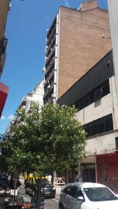 ein hohes Gebäude mit Autos vor einem Baum in der Unterkunft Retiro Apartment in Buenos Aires