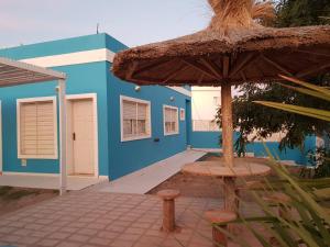 a blue building with a table and an umbrella at Aguamarina in Las Grutas