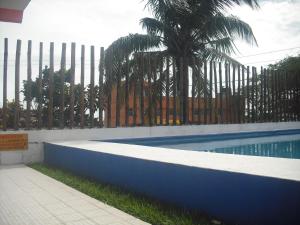 a swimming pool next to a fence with a palm tree at Hotel Villas del Rey in Chachalacas