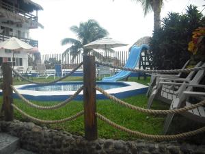 um resort com piscina com escorrega e cadeiras em Hotel Villas del Rey em Chachalacas
