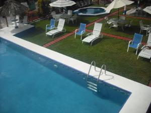 una piscina con sillas, una mesa y una piscina en Hotel Villas del Rey, en Chachalacas