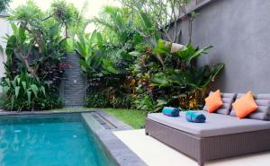 a backyard pool with a couch next to a swimming pool at Villa Sally in Canggu