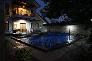 un grupo de personas en una piscina por la noche en Pesona Air - Villa and Private Pool en Depok