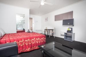 a living room with a red bed and a table at Rose Court Motel in Rotorua