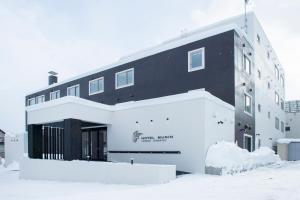 a black and white building in the snow at Hotel Munin Furano in Furano