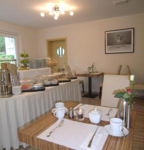 ein Esszimmer mit einem Tisch mit Tellern und Küchenutensilien in der Unterkunft Pension Delia Will in Ahlbeck