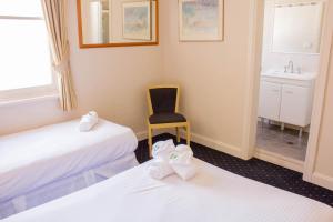 a room with two beds and a chair and a sink at Gardners Inn Hotel in Blackheath