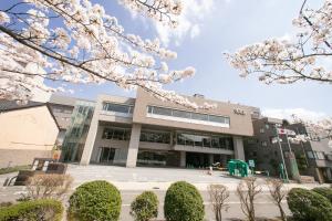 a university building with whiteakuraakura trees in front of it at KKR Hotel Kanazawa in Kanazawa