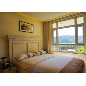 a bedroom with a bed and a large window at Tagaytay, Twinlakes, The Vineyard at Merlot in Balibaguhan