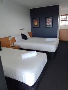 a hotel room with two beds and a desk at Annerley Motor Inn in Brisbane