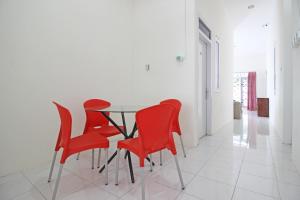 ein Esszimmer mit roten Stühlen und einem Glastisch in der Unterkunft RedDoorz near Terminal Tirtonadi in Solo