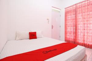 ein Schlafzimmer mit einem roten Kissen auf einem weißen Bett in der Unterkunft RedDoorz near Terminal Tirtonadi in Solo