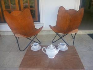 two chairs and a table with two tea sets on it at First House Mihintale in Mihintale
