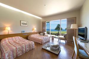 una camera d'albergo con due letti e una televisione di The Southern Links Resort Hotel a Yaese
