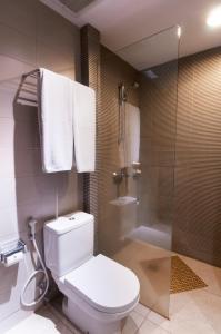 a bathroom with a toilet and a shower with towels at 100 Sunset Kuta Hotel & Ballroom in Kuta