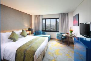 ein Hotelzimmer mit einem Bett, einem Tisch und einem TV in der Unterkunft Golden Tulip Shanghai Hongqiao - A Louvre Hotel in Shanghai