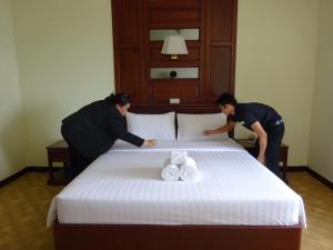 2 Personen bereiten ein Bett in einem Hotelzimmer vor in der Unterkunft MIDO Hotel in Bangkok