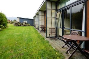 a patio with a table and chairs on the side of a house at Sunset Motel in Fox Glacier